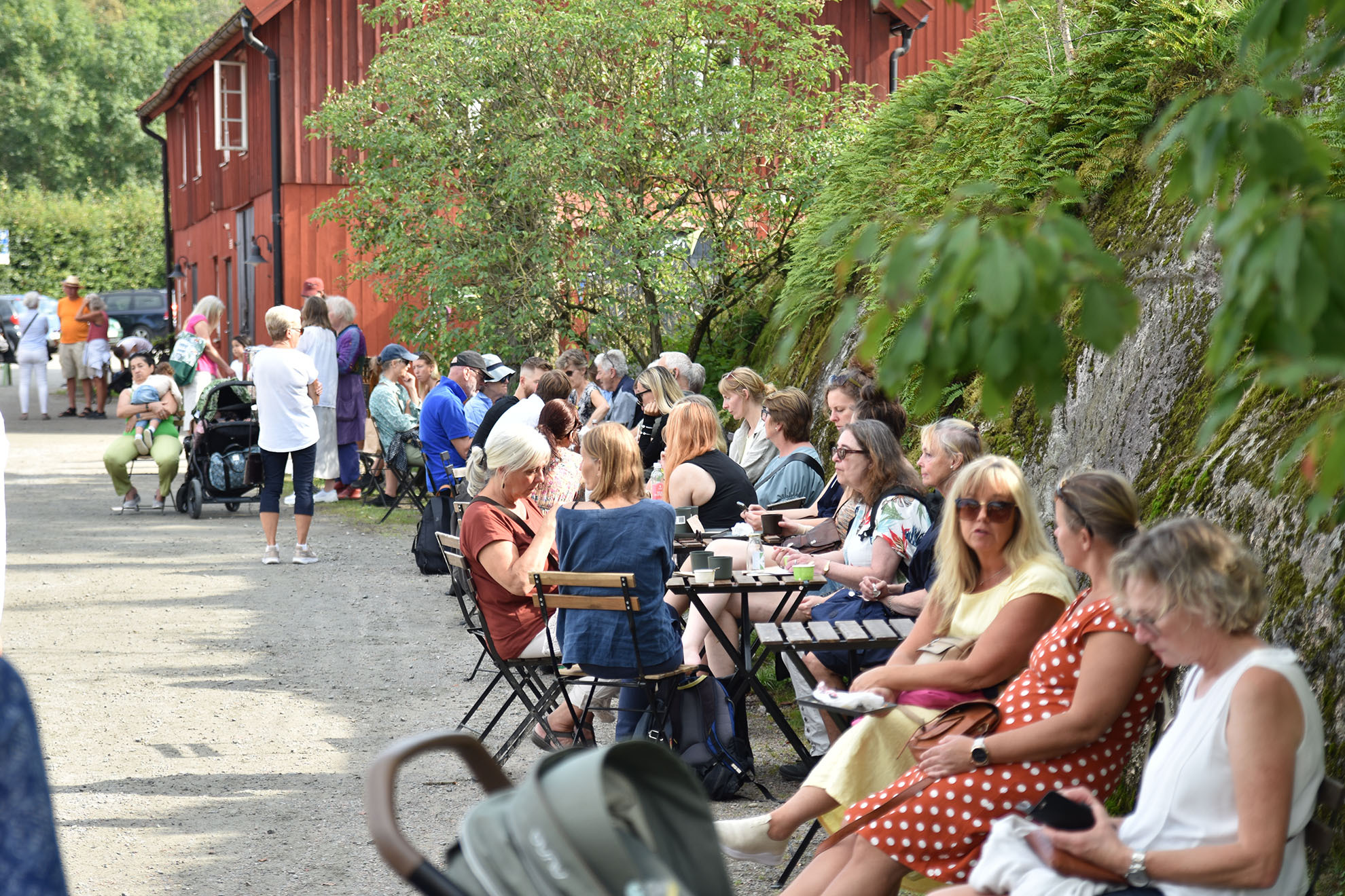 Människor sitter vid bord utomhus en solig dag