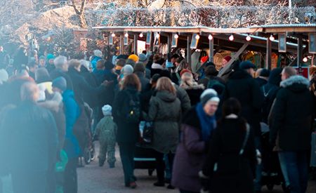 Julmarknad på Gunnebo slott med ett myller av människor som rör sig förbi marknadsstånden.